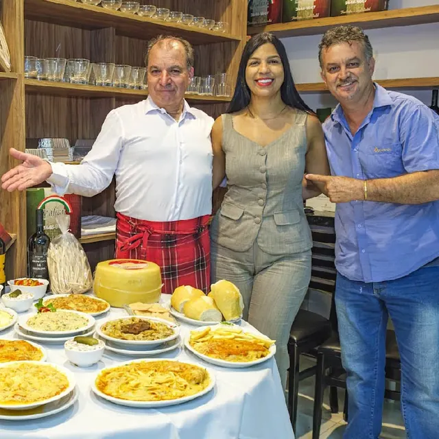 Proprietário recebendo convidados ao lado da mesa de massas